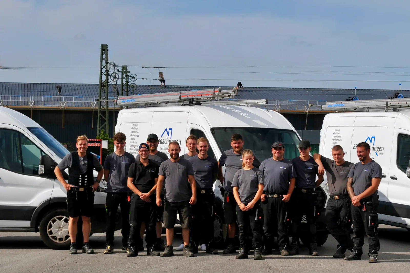 Das gesamte Handwerker-Team von BS Bedachungen vor den Firmentransportern auf dem Betriebshof in Willich
